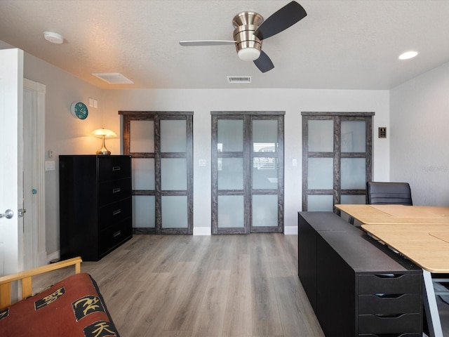 interior space with a textured ceiling, ceiling fan, and light wood-type flooring