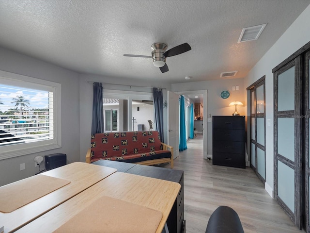 bedroom with a textured ceiling, ceiling fan, and light wood-type flooring