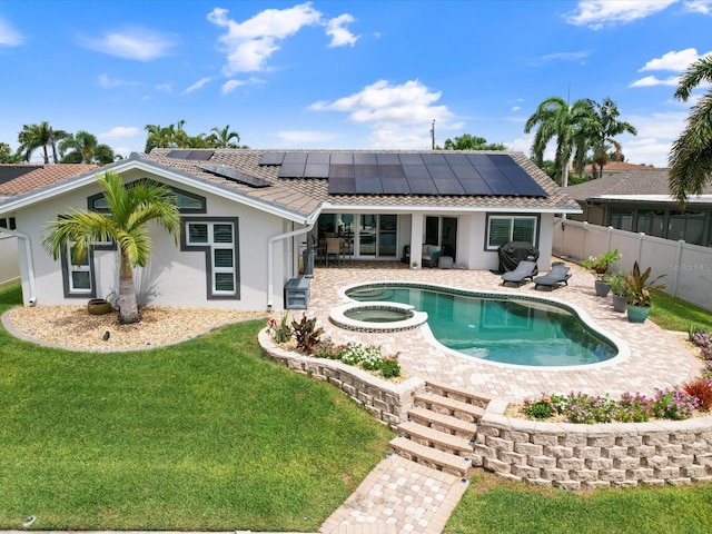 back of house with a pool with hot tub, a patio area, solar panels, and a lawn