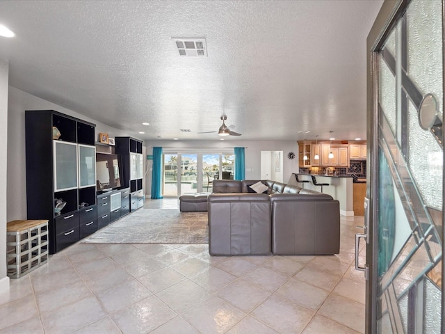 tiled living room with ceiling fan and a textured ceiling