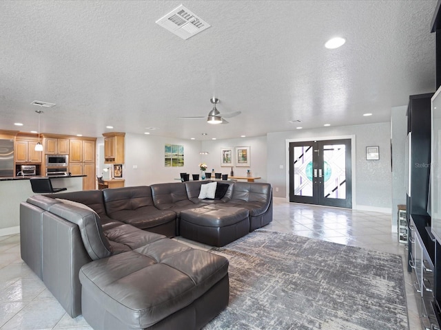 living room featuring french doors, ceiling fan, light tile patterned flooring, and a textured ceiling