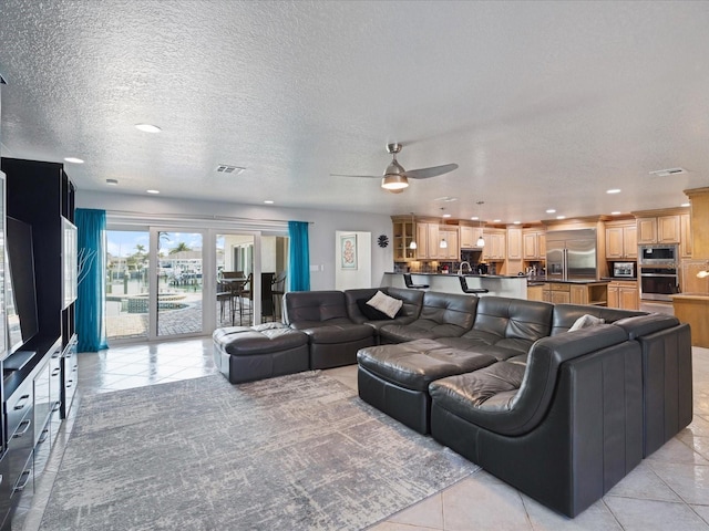 living room featuring ceiling fan, light tile patterned floors, and a textured ceiling