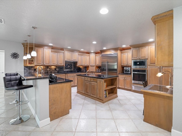 kitchen with a kitchen bar, built in appliances, a center island, kitchen peninsula, and decorative backsplash