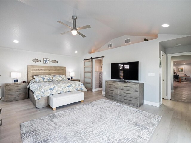 bedroom with ceiling fan, lofted ceiling, a barn door, and light hardwood / wood-style flooring