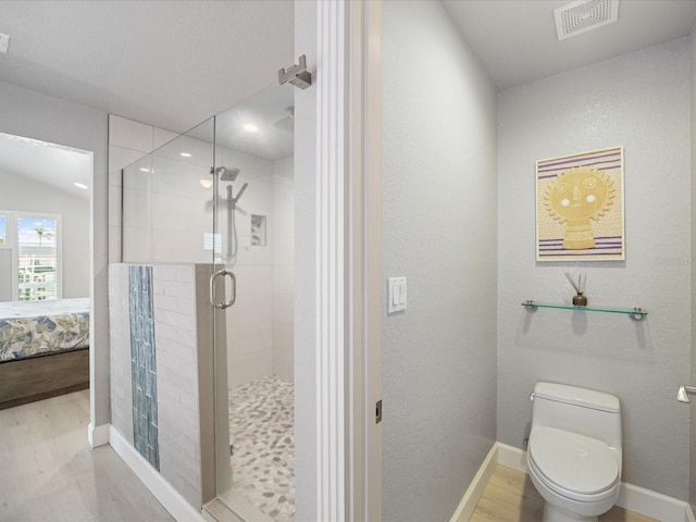 bathroom with hardwood / wood-style flooring, toilet, and a shower with shower door