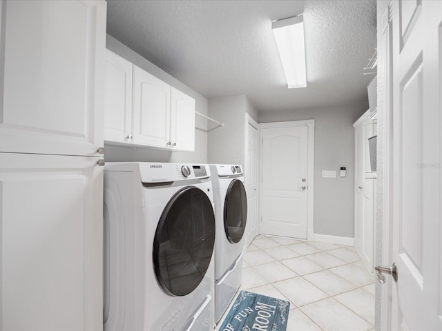 laundry area with washing machine and dryer, cabinets, a textured ceiling, and light tile patterned flooring