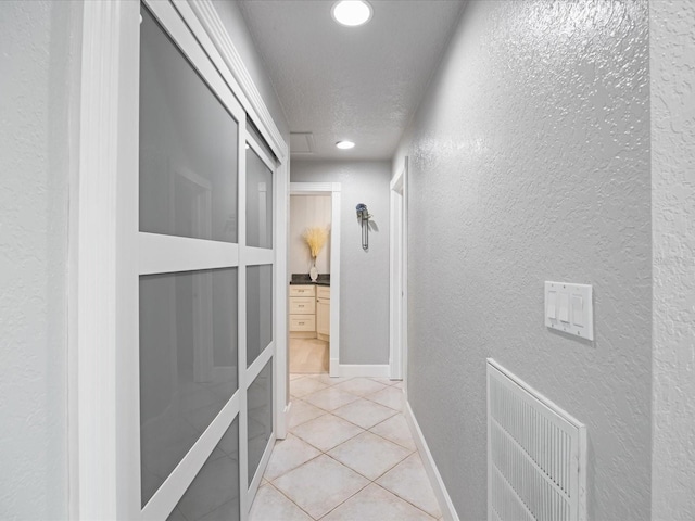 hallway featuring a textured ceiling and light tile patterned floors