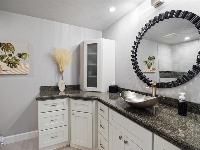 kitchen featuring white cabinetry, sink, dark stone counters, and a textured ceiling