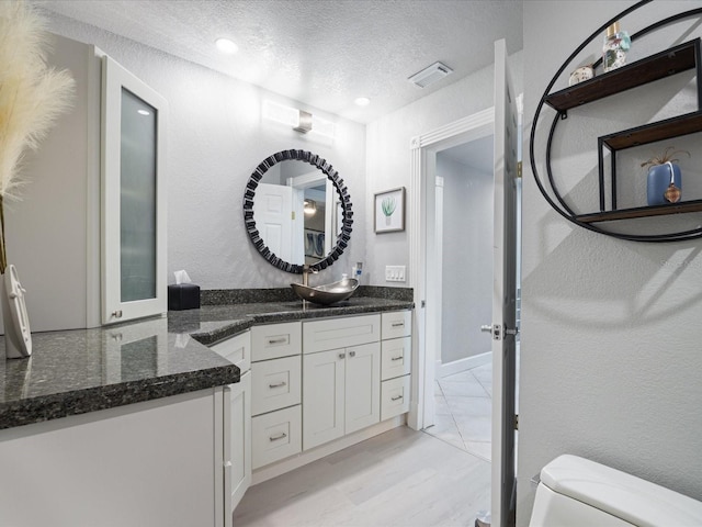 bathroom with vanity, hardwood / wood-style flooring, toilet, and a textured ceiling