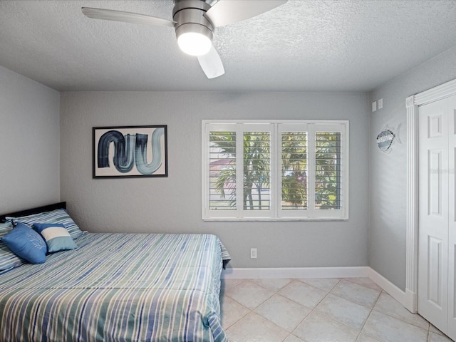 bedroom with a textured ceiling, ceiling fan, and light tile patterned flooring