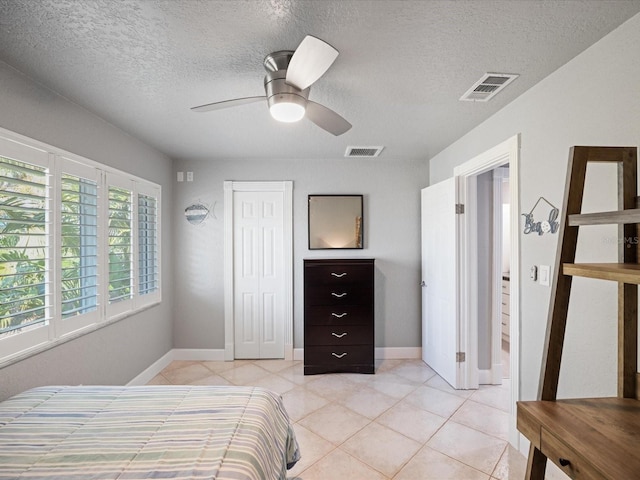 bedroom with ceiling fan, a textured ceiling, a closet, and light tile patterned floors