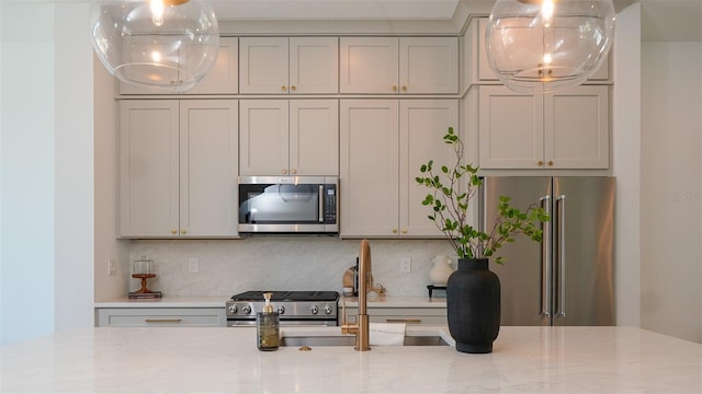 kitchen with sink, gray cabinetry, backsplash, high end appliances, and light stone countertops