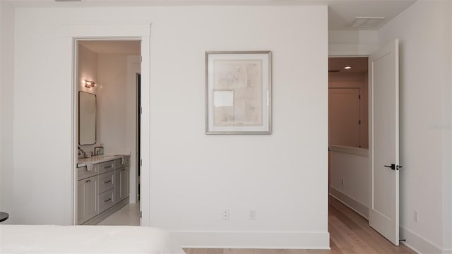 bedroom featuring ensuite bath and light hardwood / wood-style flooring