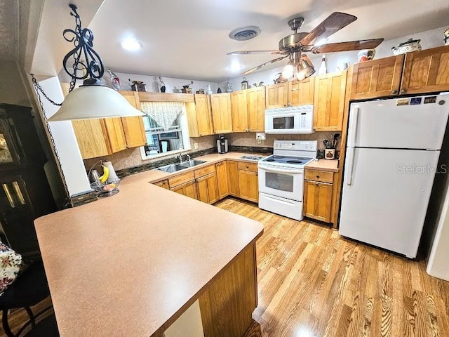 kitchen with pendant lighting, sink, kitchen peninsula, white appliances, and light hardwood / wood-style flooring