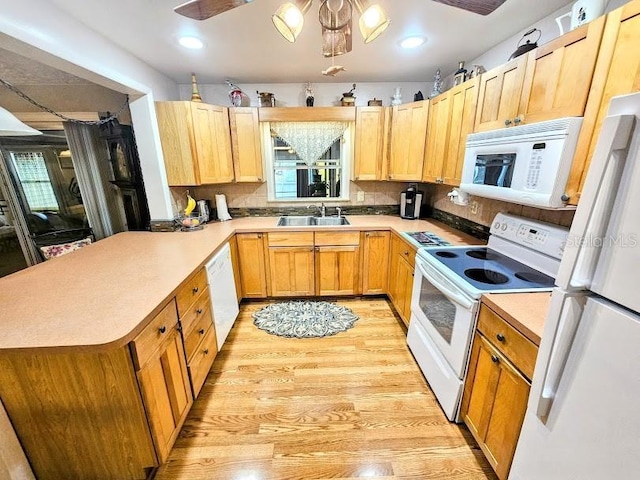 kitchen featuring tasteful backsplash, sink, light hardwood / wood-style floors, kitchen peninsula, and white appliances