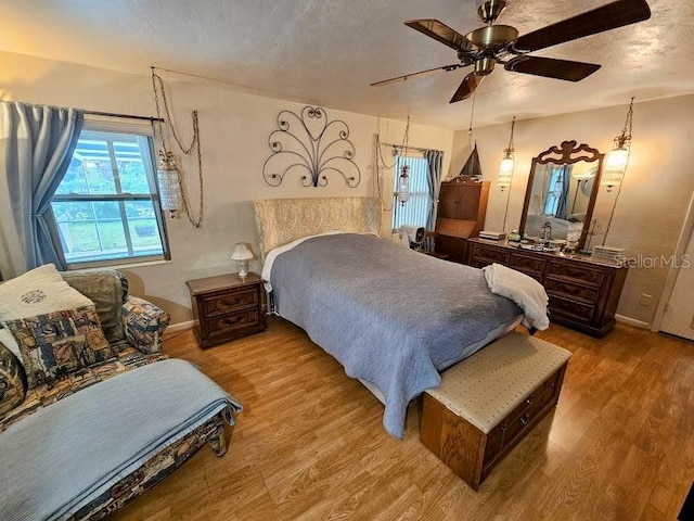 bedroom featuring ceiling fan, light hardwood / wood-style flooring, and a textured ceiling