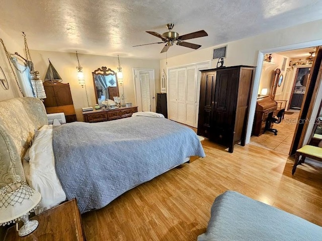 bedroom with ceiling fan, light hardwood / wood-style flooring, and a textured ceiling