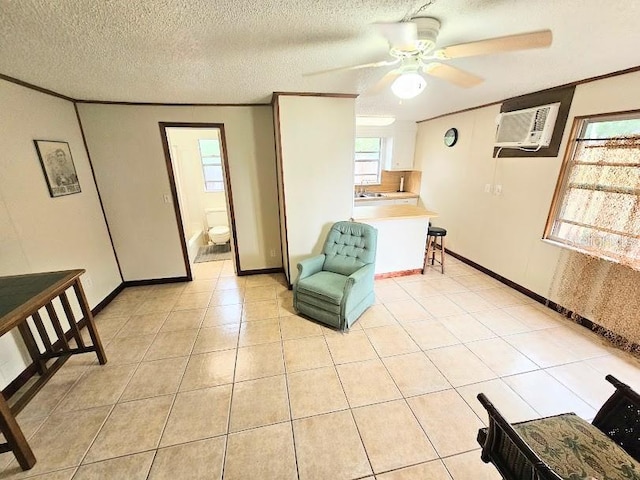 living area featuring an AC wall unit, ornamental molding, light tile patterned floors, ceiling fan, and a textured ceiling