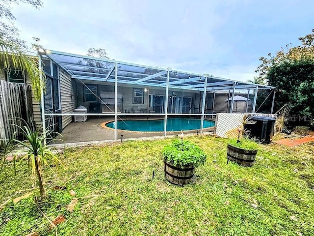 exterior space with a grill, a yard, and glass enclosure