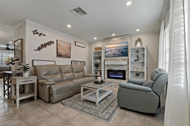 tiled living room with a fireplace, ornamental molding, and ceiling fan