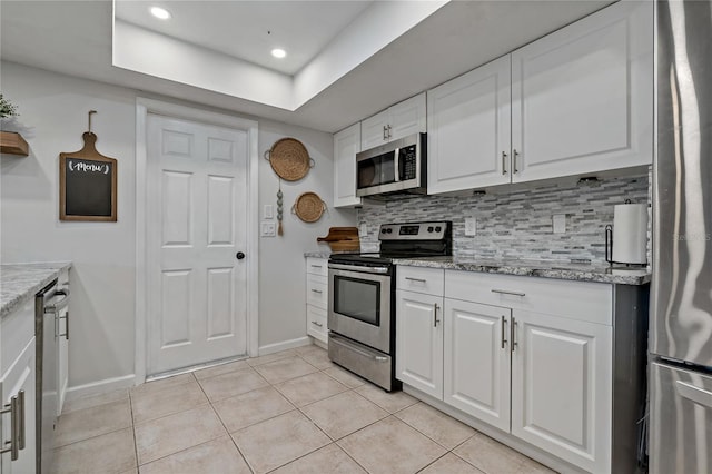 kitchen featuring stainless steel appliances, white cabinetry, light stone countertops, and tasteful backsplash