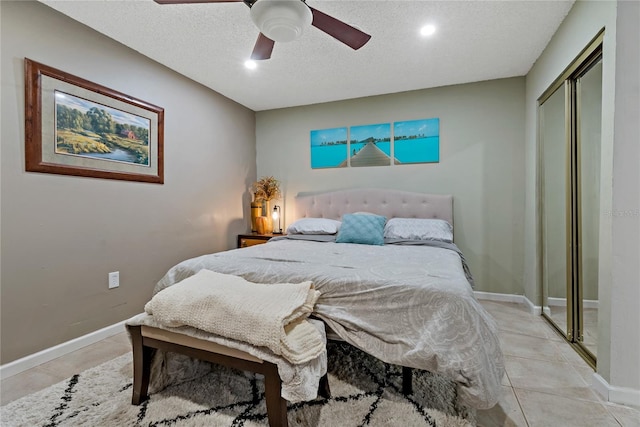 bedroom featuring light tile patterned flooring, ceiling fan, a closet, and a textured ceiling