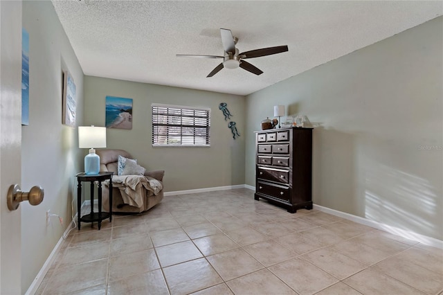 living area with ceiling fan, a textured ceiling, and light tile patterned floors