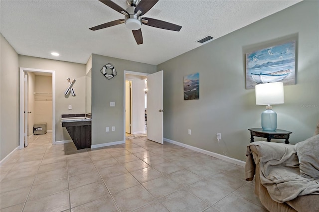 interior space with ceiling fan, light tile patterned floors, and a textured ceiling