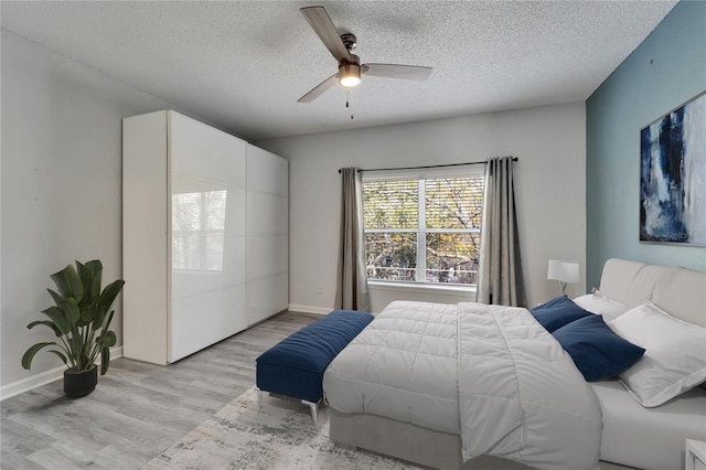 bedroom featuring ceiling fan, a textured ceiling, and light wood-type flooring