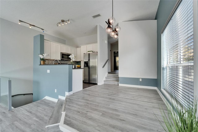 kitchen featuring white cabinetry, hardwood / wood-style floors, stainless steel appliances, decorative light fixtures, and kitchen peninsula