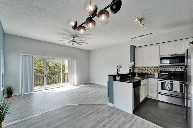 kitchen with appliances with stainless steel finishes, white cabinetry, sink, decorative backsplash, and dark wood-type flooring