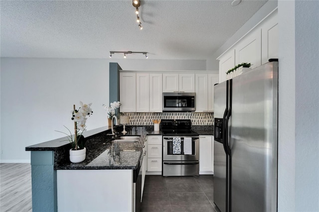 kitchen with sink, tasteful backsplash, dark stone counters, stainless steel appliances, and white cabinets