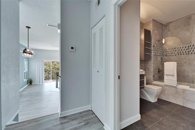 hallway featuring dark wood-type flooring, a textured ceiling, and an inviting chandelier