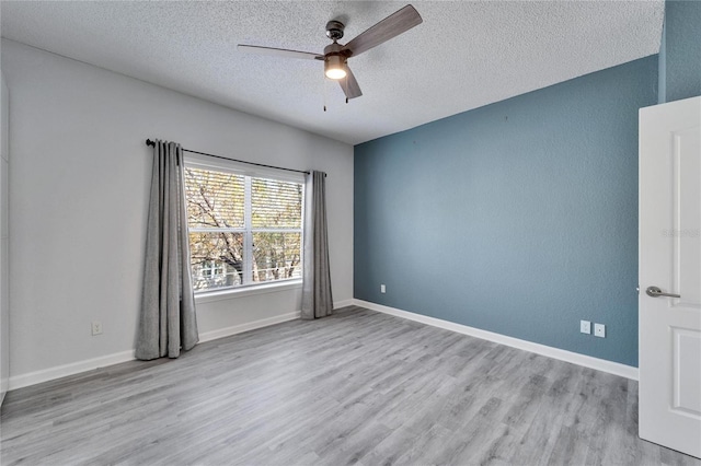 empty room with a textured ceiling, light hardwood / wood-style floors, and ceiling fan