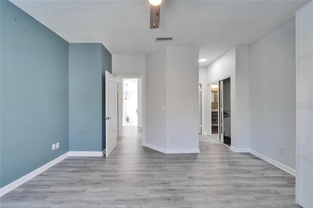 unfurnished room with a textured ceiling and light wood-type flooring