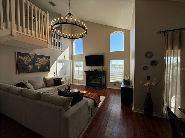 living room with a notable chandelier, a towering ceiling, and dark hardwood / wood-style floors