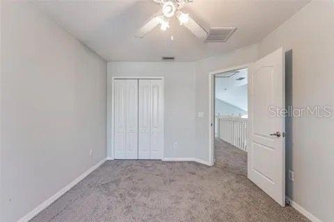 unfurnished bedroom featuring light colored carpet, ceiling fan, and a closet