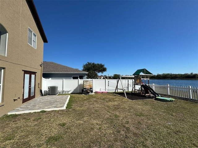 view of yard with central AC, a water view, a patio area, a playground, and french doors