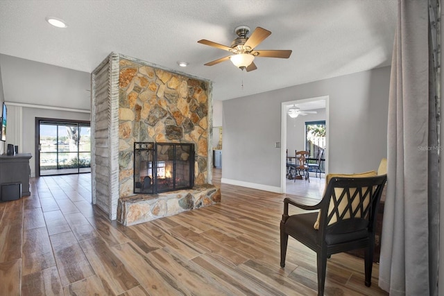 living room with wood-type flooring, a healthy amount of sunlight, a textured ceiling, and a fireplace