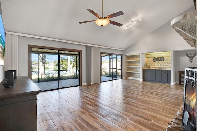 unfurnished living room featuring ceiling fan, vaulted ceiling, and a textured ceiling