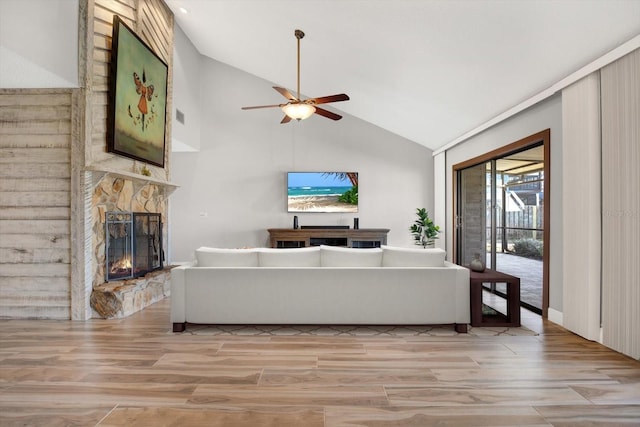 living room with ceiling fan, lofted ceiling, light wood-type flooring, and a fireplace