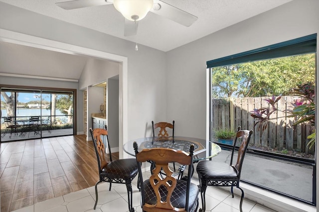 dining area featuring ceiling fan, vaulted ceiling, and a textured ceiling