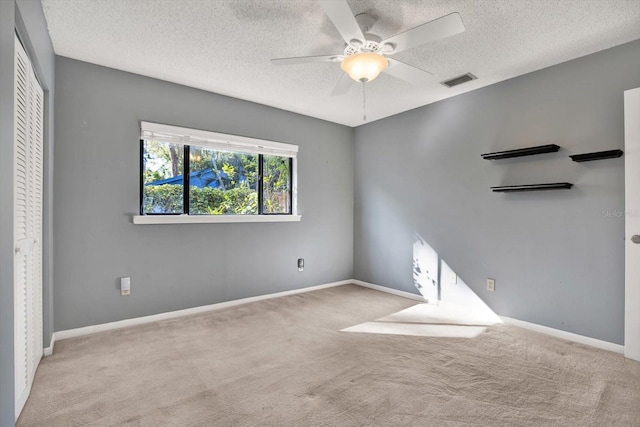 carpeted empty room featuring ceiling fan and a textured ceiling