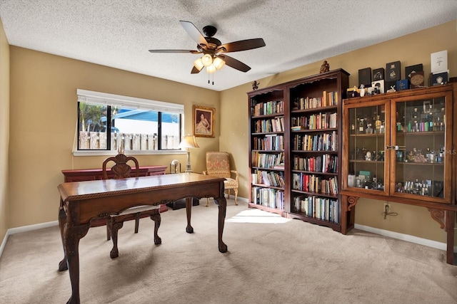 carpeted office featuring ceiling fan and a textured ceiling