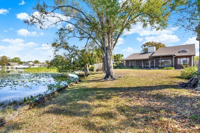 view of yard featuring a water view and a sunroom