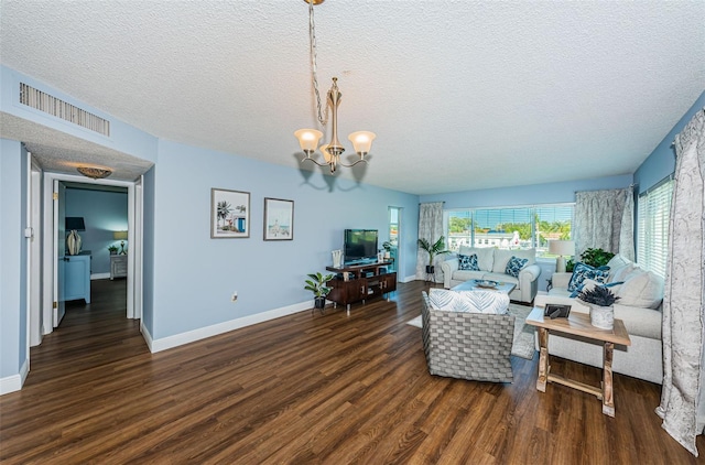 living room featuring a textured ceiling, dark wood-type flooring, and a chandelier