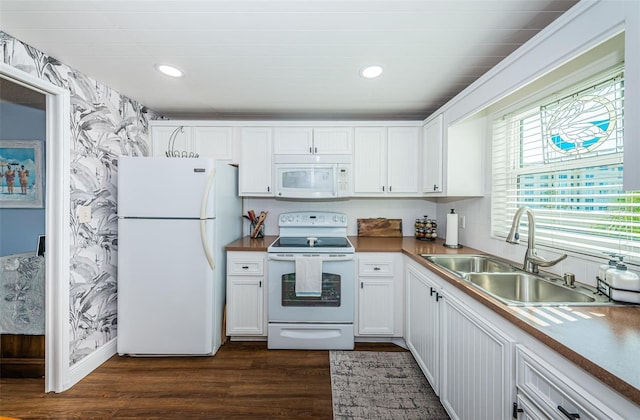 kitchen with dark hardwood / wood-style flooring, sink, white cabinets, and white appliances