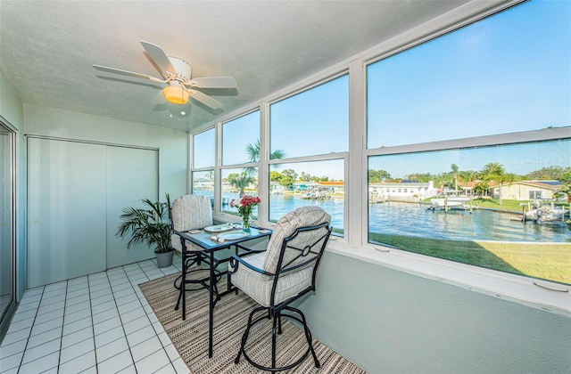 sunroom featuring ceiling fan and a water view