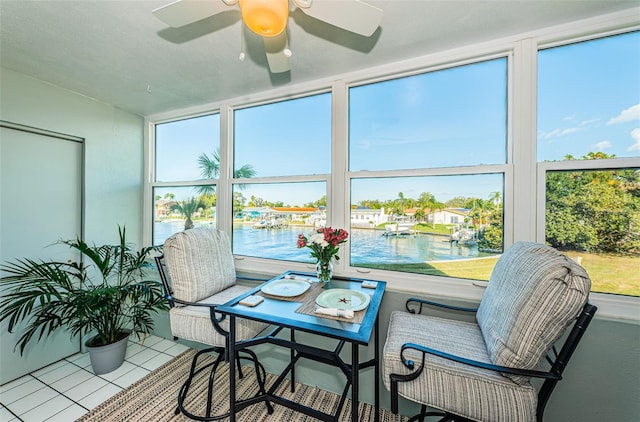 sunroom / solarium featuring ceiling fan, a healthy amount of sunlight, and a water view