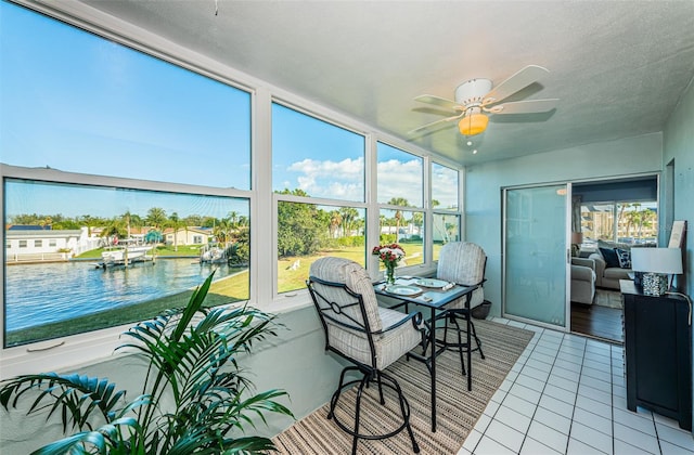 sunroom / solarium featuring a water view and ceiling fan